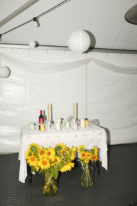 Juhlatilaisuus teltassa, kukkia ja koristeita.